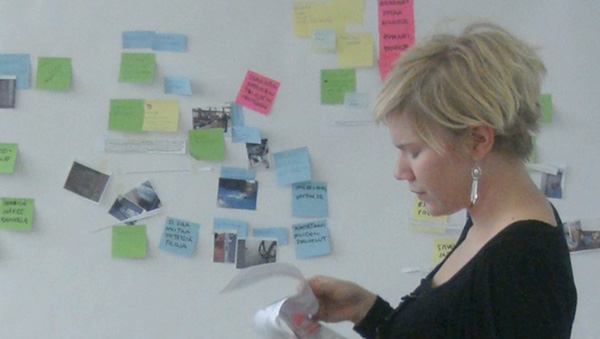Vilma sorting research material to a canvas with post-it notes